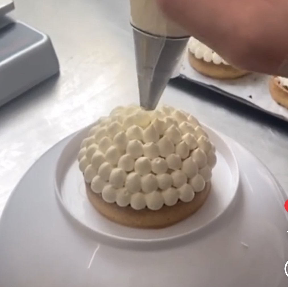 Gros plan sur le pochage de crème sur une tartelette